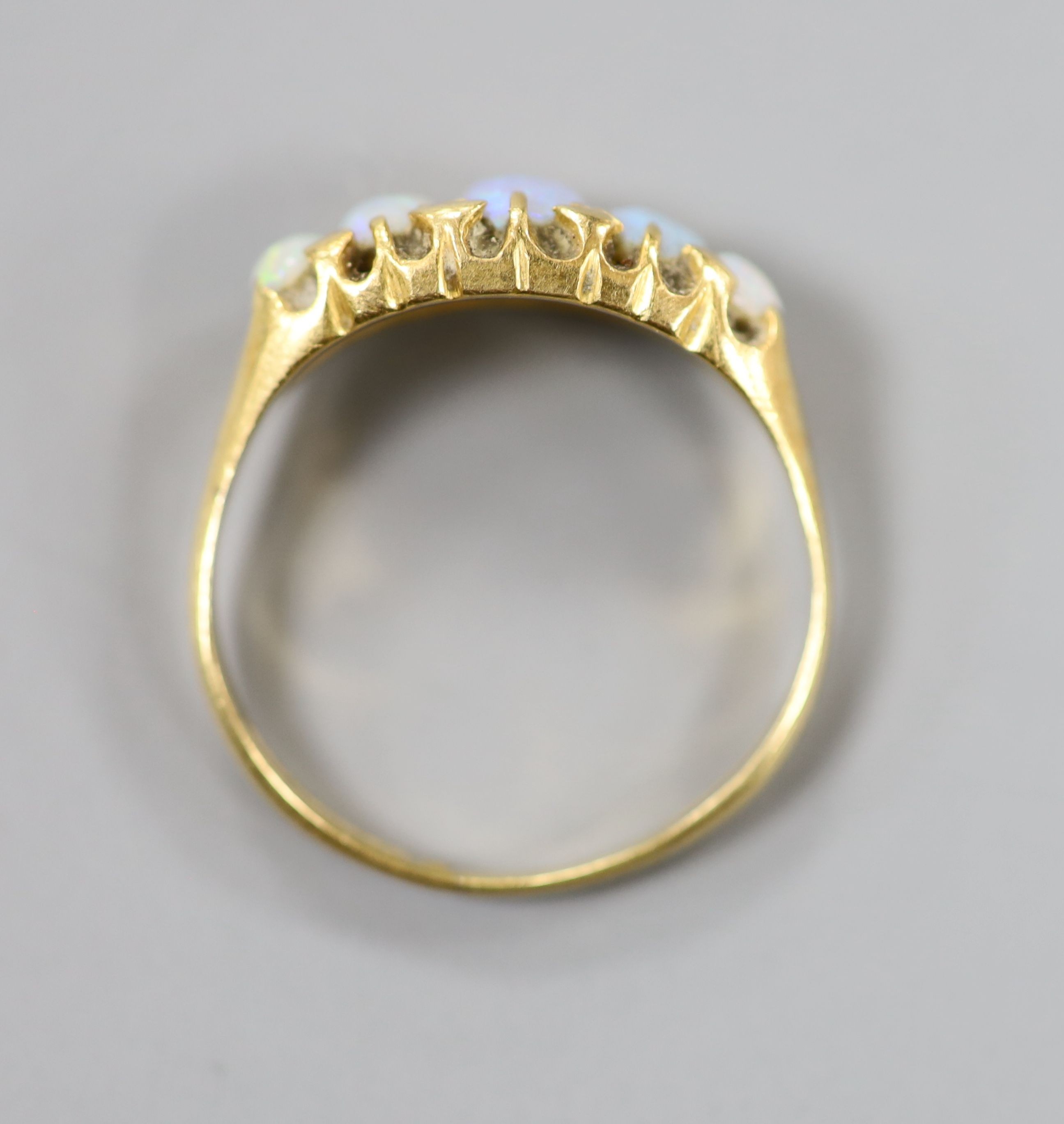 An 18ct gold and graduated oval white opal set half hoop ring, size Q/R, gross weight 3.4 grams.